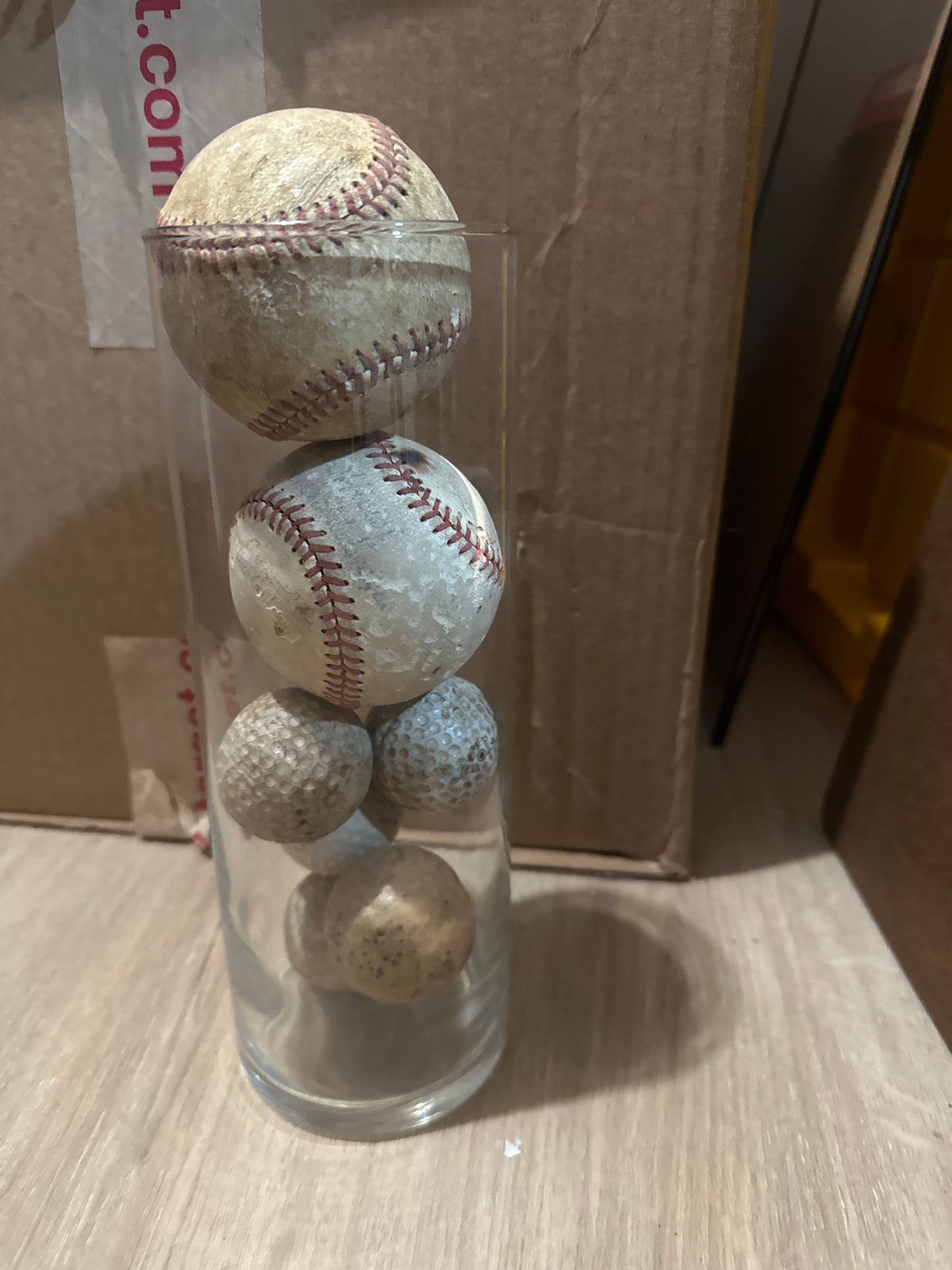Glass vase of baseballs and golf balls